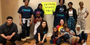 A group of young adults poses for a photo with a sign that says "Elevate Youth Voice."